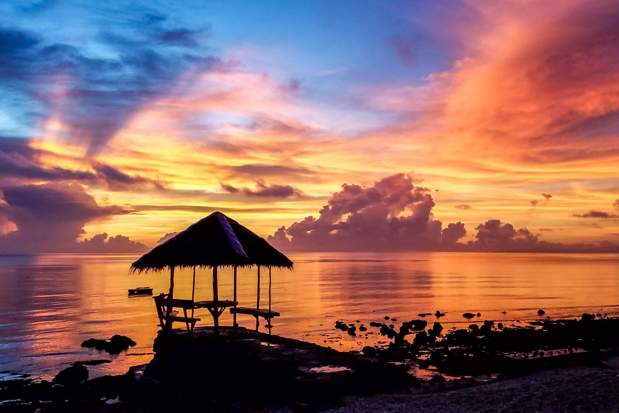 Silhouette of cottage on beach at sunset