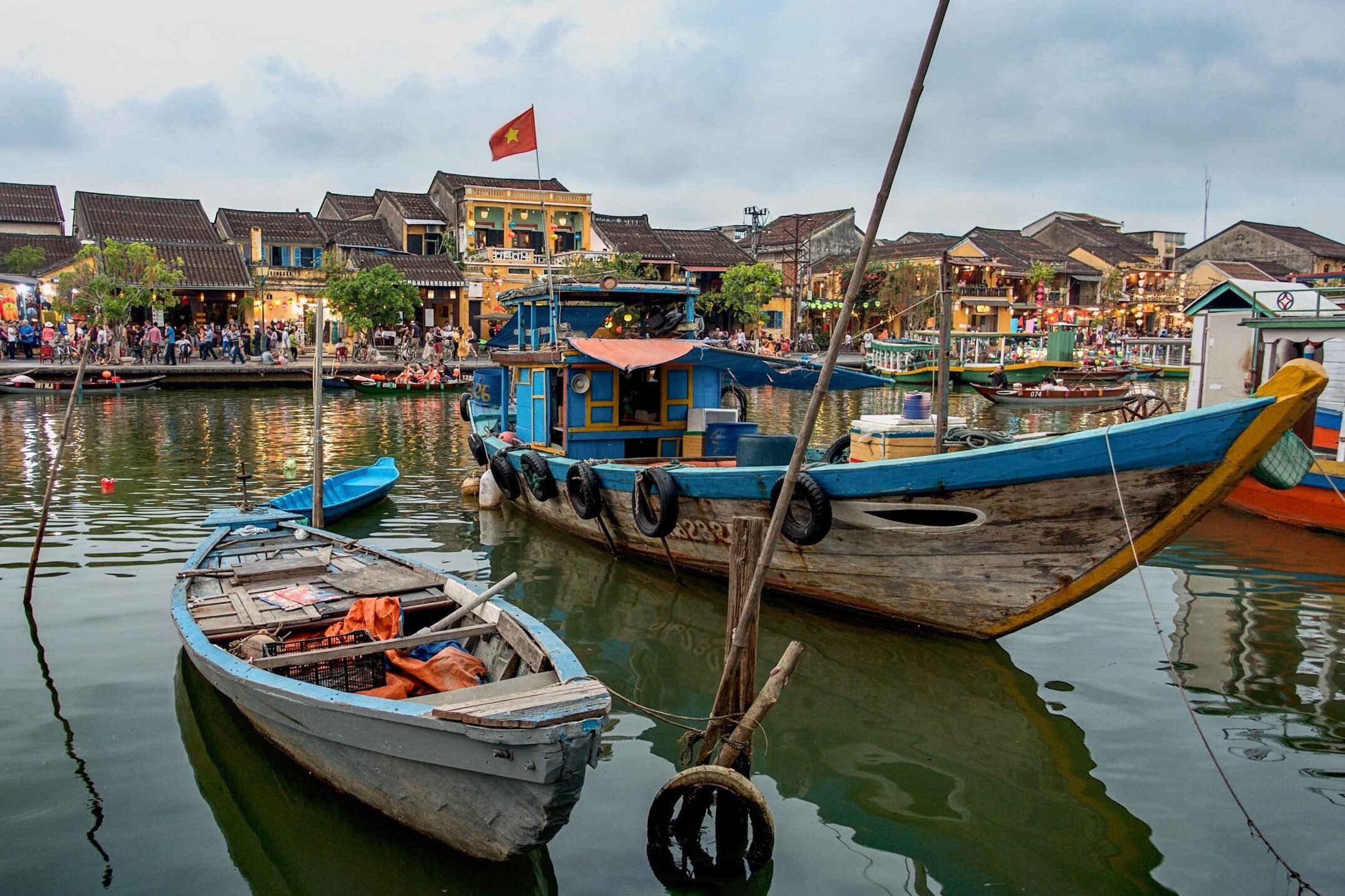 Two boats docked on a river in front of old shophouses