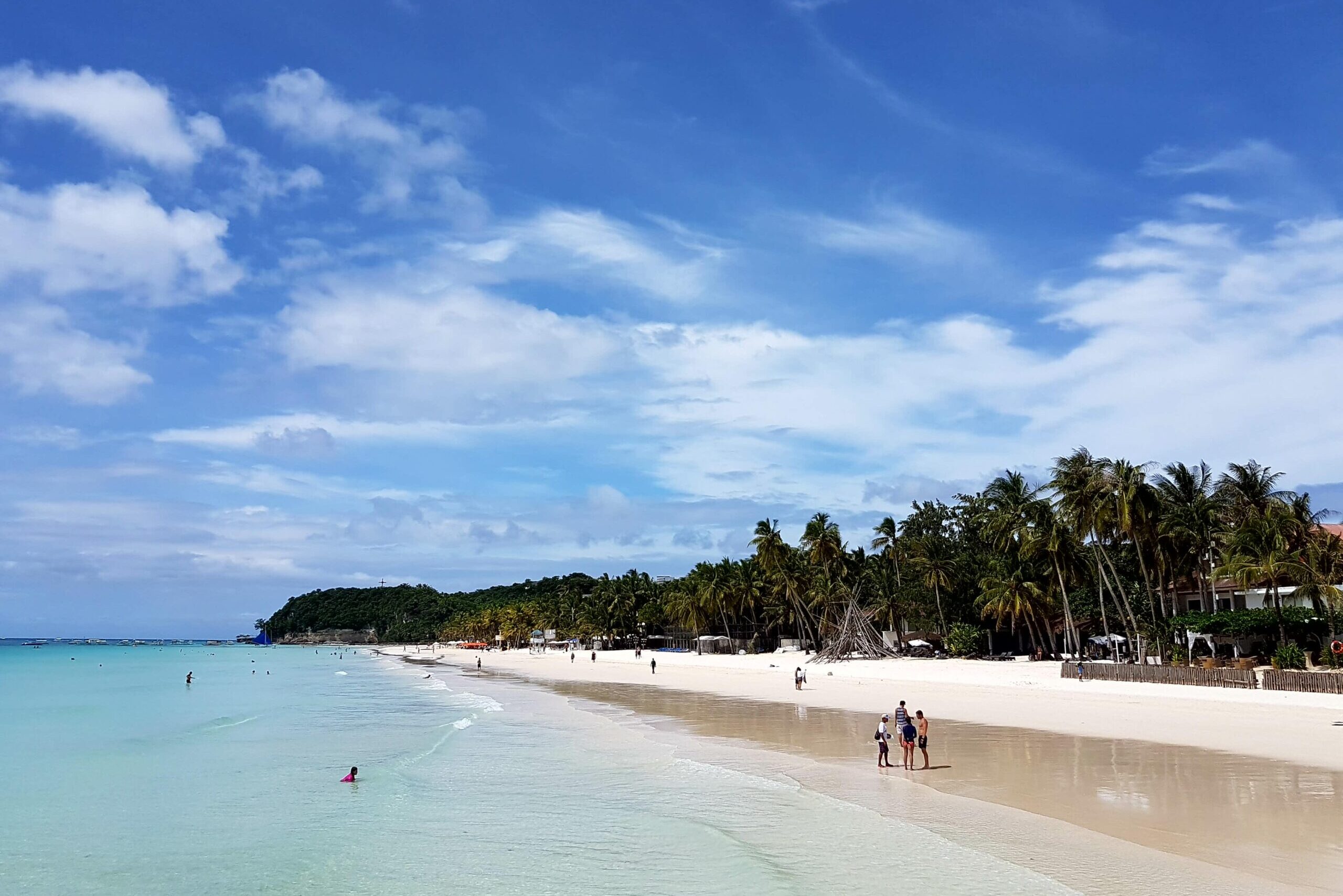 White sand beach and turquoise blue sea with palm trees and blue sky