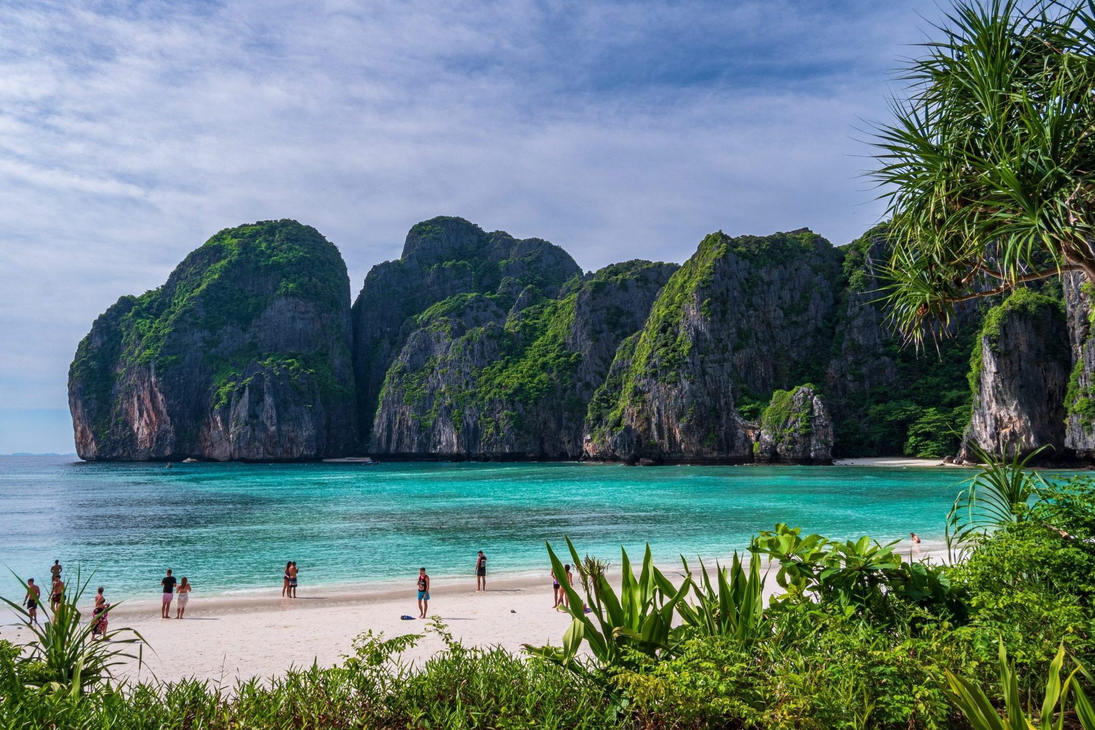 People on white sand beach surrounded by limestone karsts