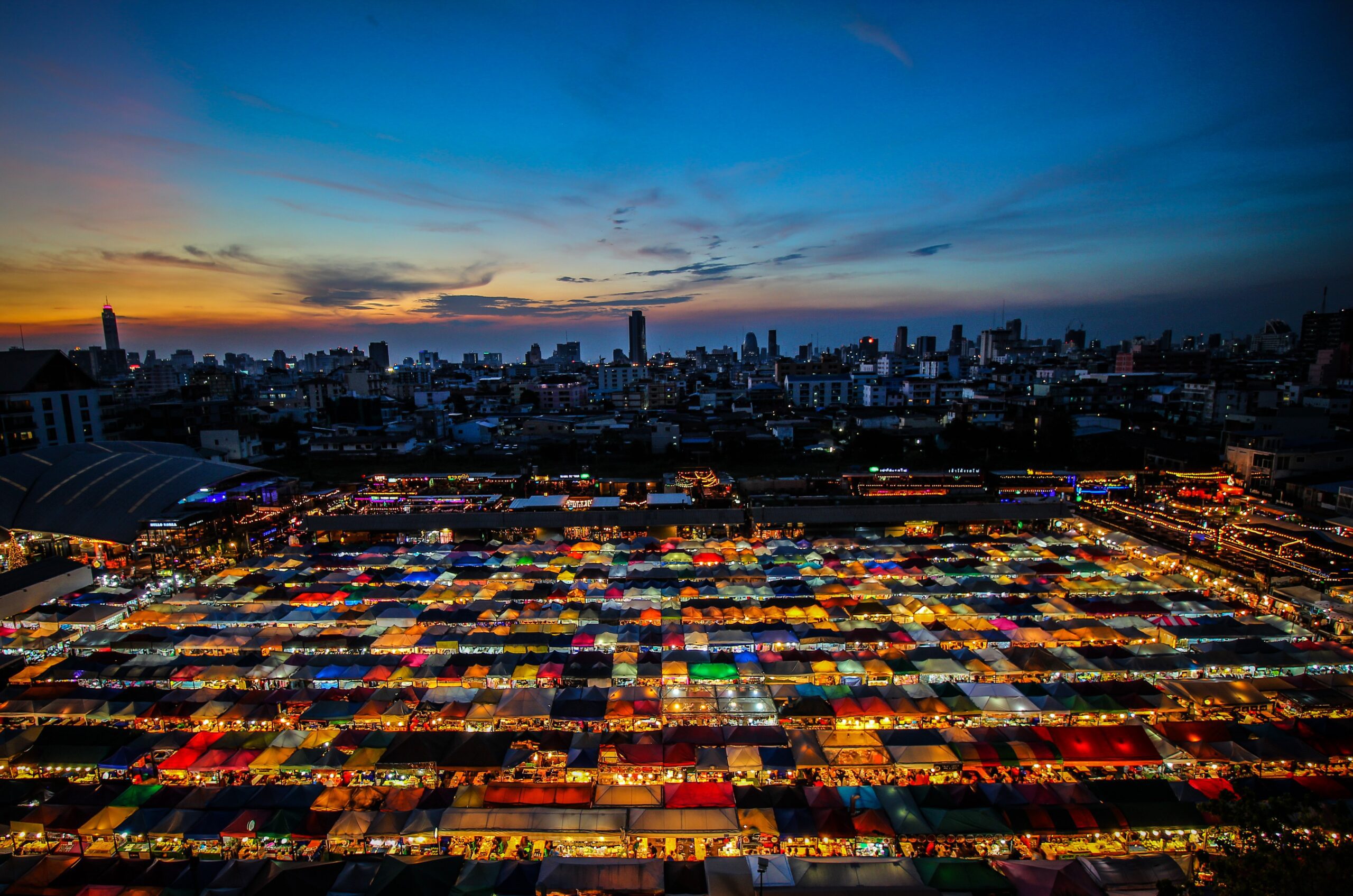 Colorful night market tents and Bangkok city skyline seen from above