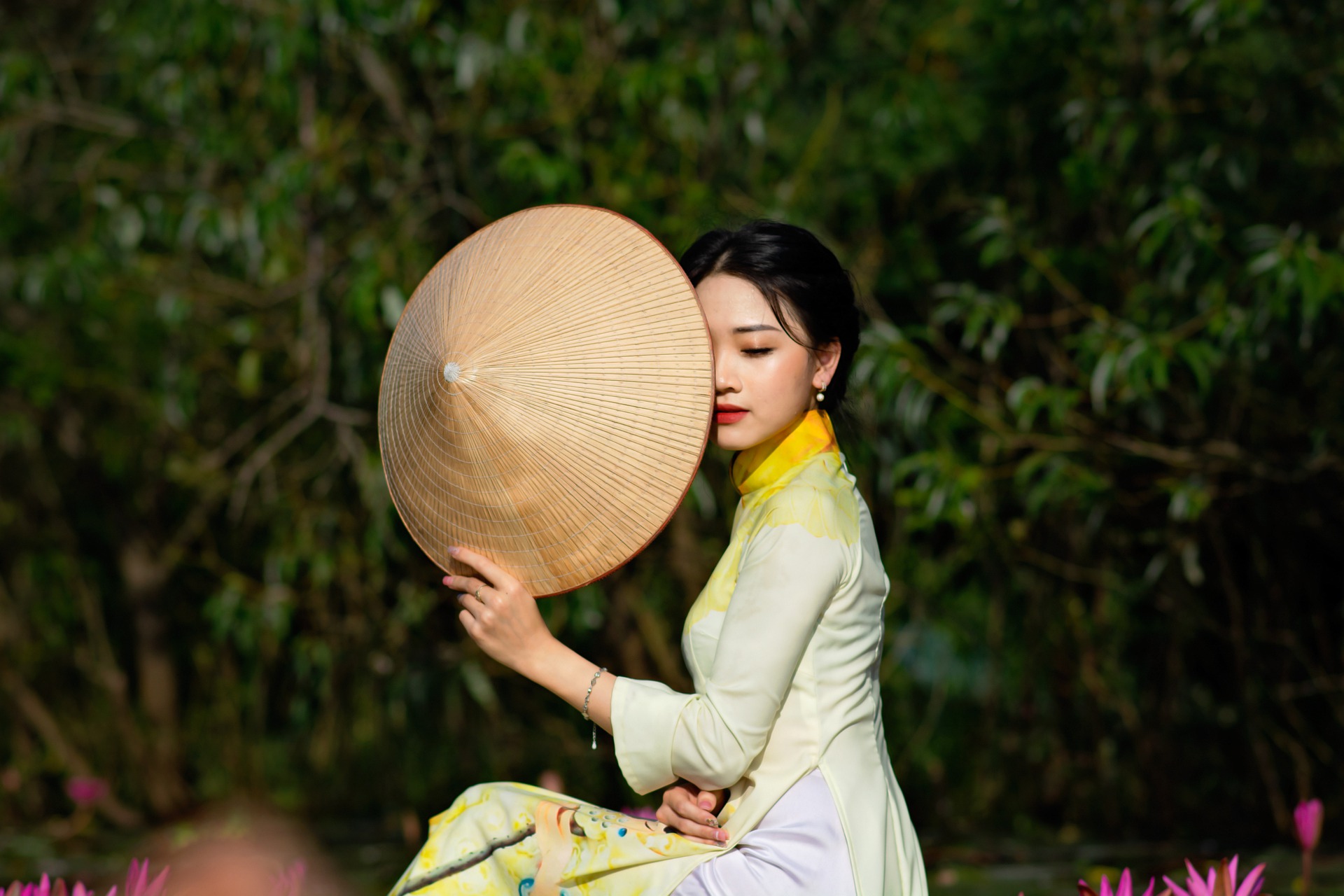 Vietnamese woman with traditional attire holding a traditional hat