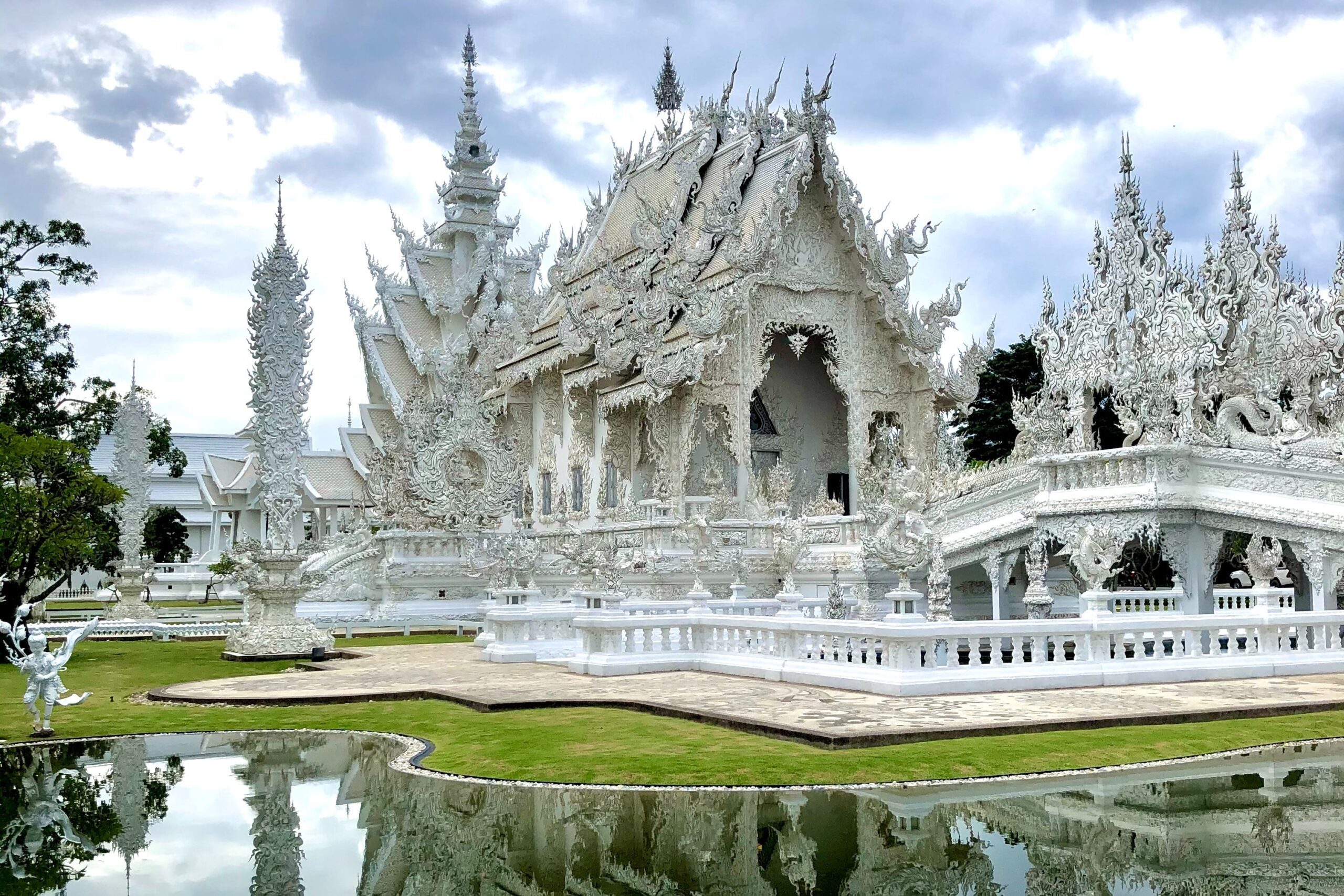 Intricate white Buddhist temple next to a pond