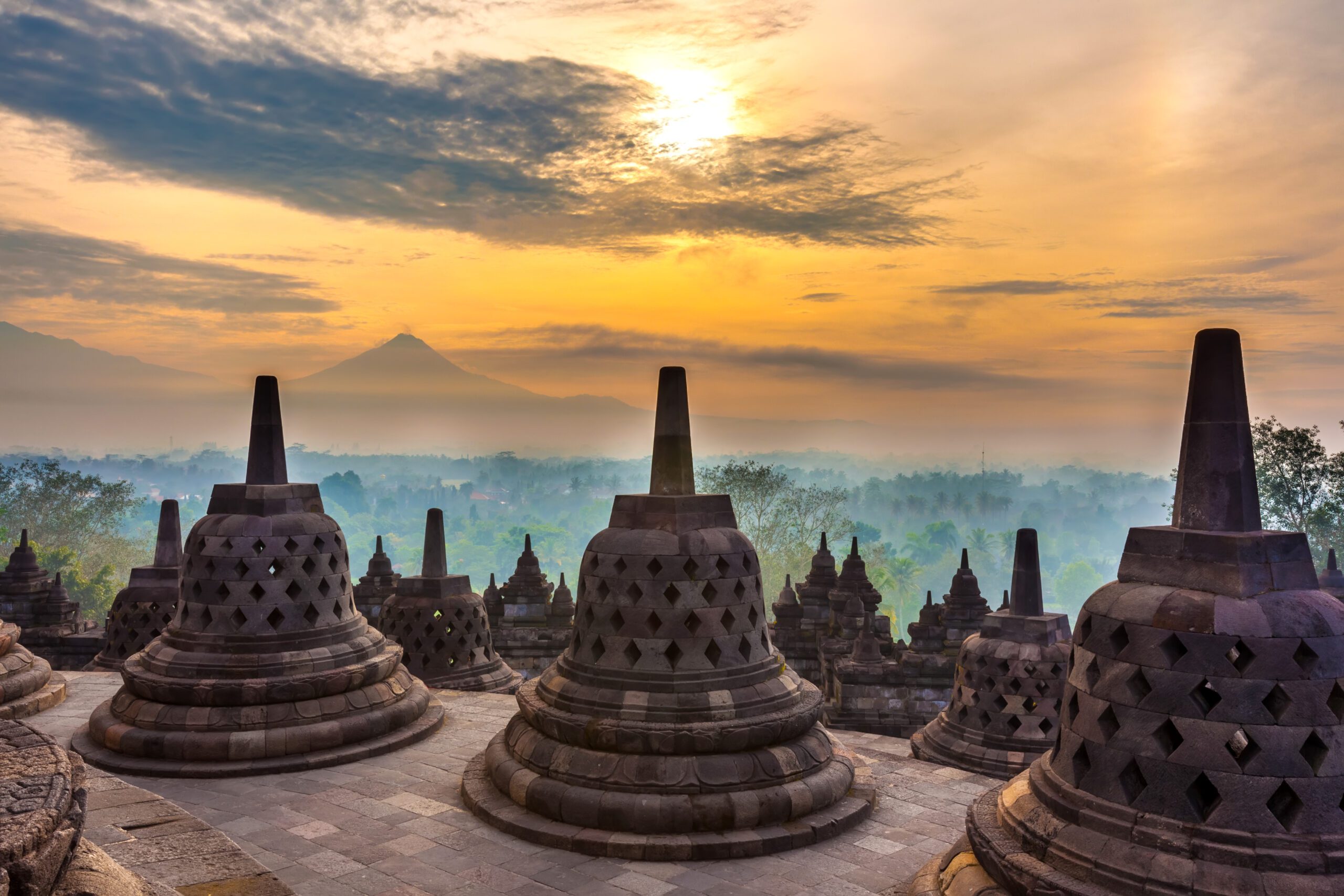 Buddhist stupas against a misty sunrise landscape